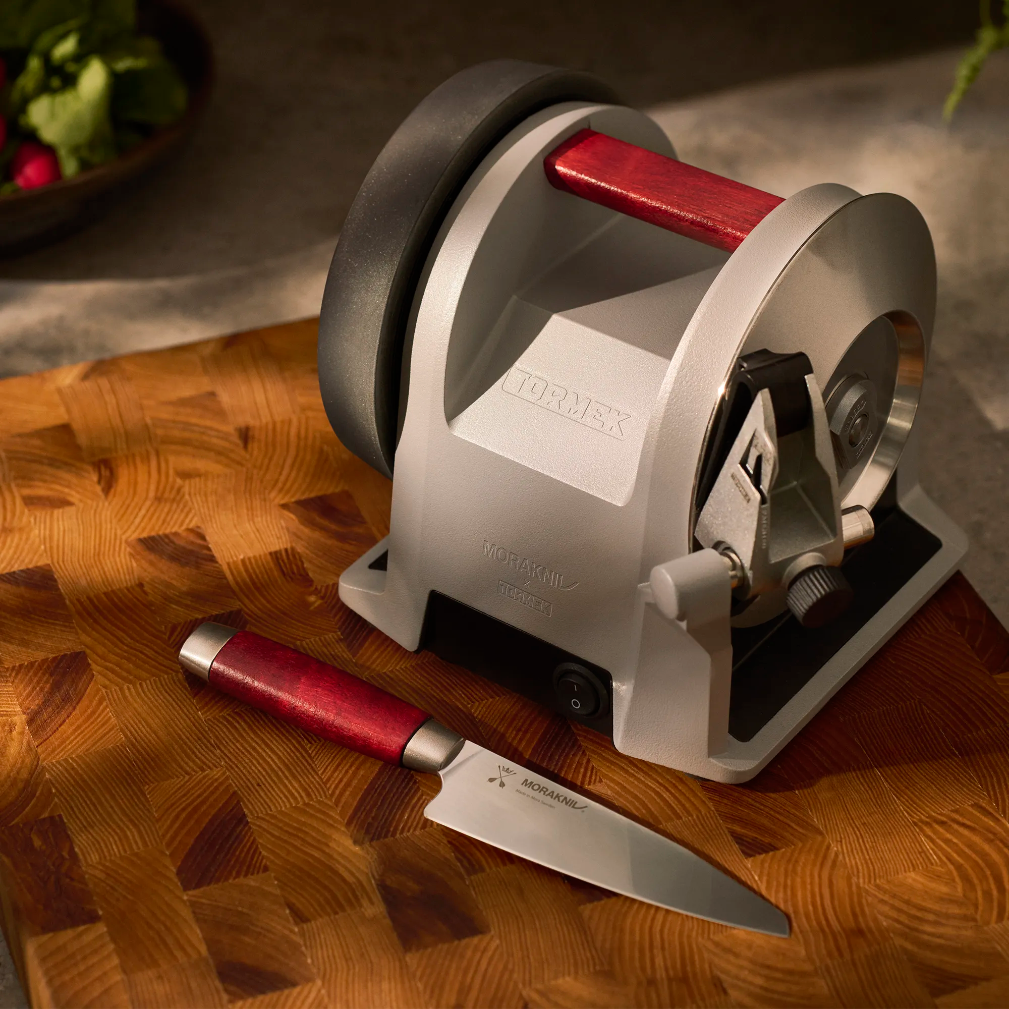 A Tormek T-1 Morakniv 1891 with a Morakniv Classic 1891 Utility Knife laying in front of it on a cutting board.