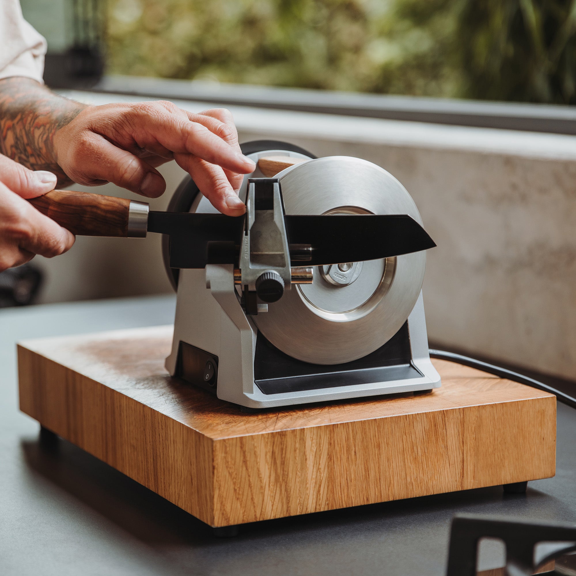 A person sharpening a knife on the Tormek T-1 Zinc Gray.