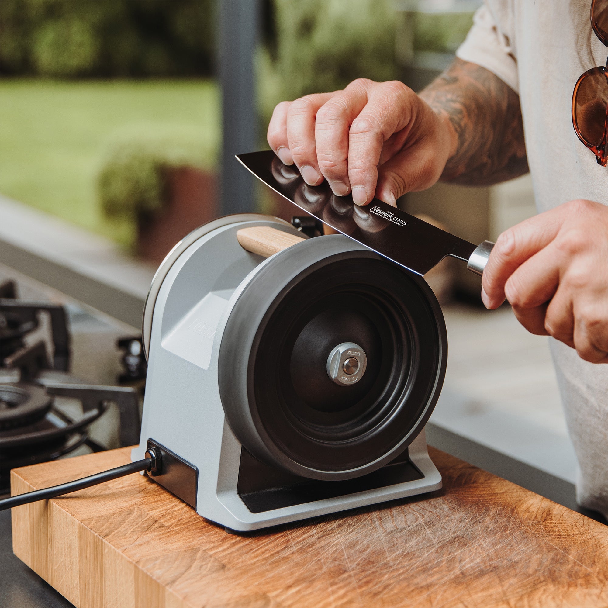 A person honing a knife on the Tormek T-1 Zinc Gray.