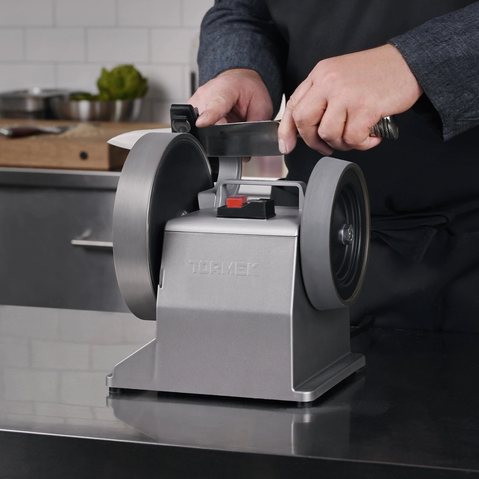 a chef is sharpening his knife on the Tormek T-2 PRO Kitchen Knife Sharpener